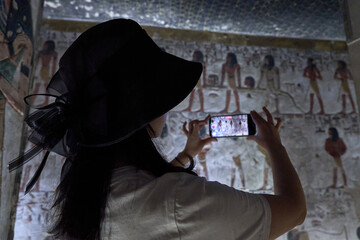 a tourist takes photos of King Seti tomb at the Valley of Kings .Luxor . Egypt. Hieroglyphics in King Seti tomb.wall reliefs showing the Book of Gates in the Tomb of Seti I at Valley of Kings