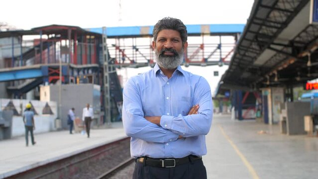 Portrait of a businessman posing for the camera standing at a railway station in Delhi NCR  growing Indian economy  public sector. A smiling middle-aged man at a railway platform in India - public ...