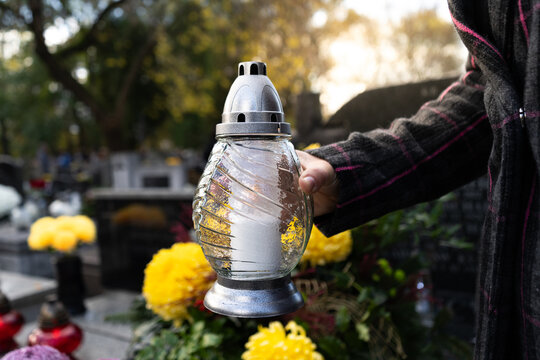 Woman holding cemetery grave candle glass lantern. Memorial light remembrance snitch or znicz. All Saints' Day, Feast of All Souls. Commemoration of All the Faithful Departed and the Day of the Dead.