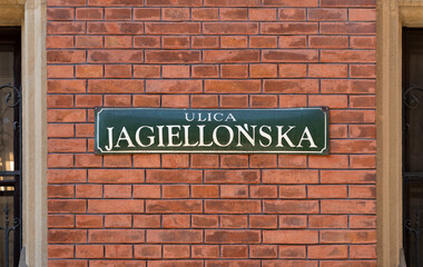 Fototapeta na wymiar Jagiellońska street name sign in the Old Town district of Krakow, Poland. Information signage plate on building brick wall in Kraków. Historic Jagiellonska street in Cracow.