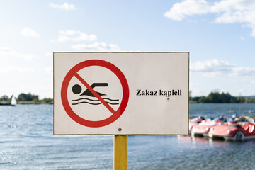 No Swimming sign post plaque, with water in background. No swim area signage pillar, mounted on the...