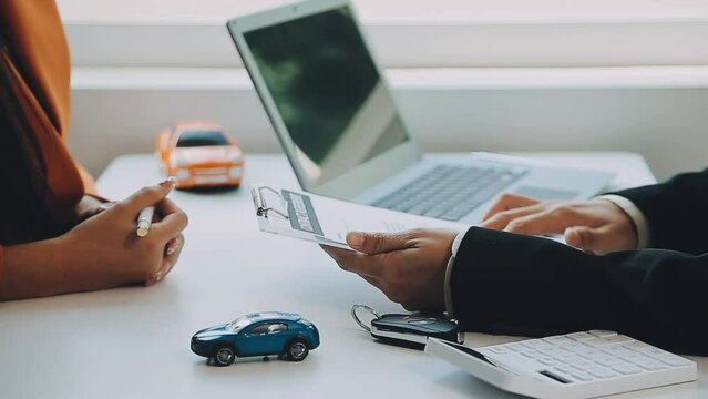 Salesman guiding customer seated at table. Car business. Car sale. Dealership closing. and the new owner has entered into a contract The idea of ​​selling and renting a car with insurance.