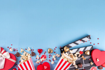 Fototapeta na wymiar Romantic date on Valentine's Day February 14. Love movie marathon, date at cinema theater. Clapperboard, popcorn buckets, heart decor and chocolates on red background flat lay copy space