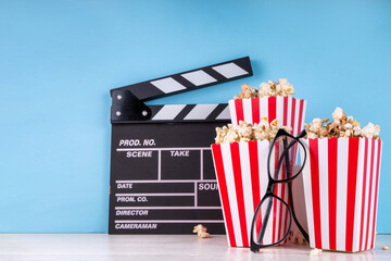 Cinema, film and movie night watching concept. Clapperboard, striped popcorn bucket boxes, with...