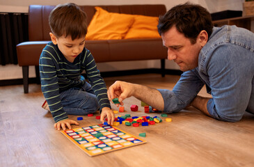 Happy young handsome father playing with little kid, son, with wooden blocks building