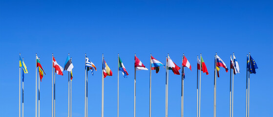 Poles with flags of the countries members of the European Union on blue sky background at the...