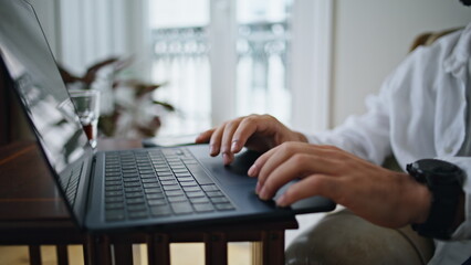 Guy hands typing keyboard laptop at apartment closeup. Man arms pressing buttons