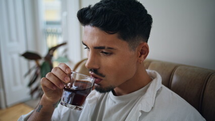 Resting man drinking whiskey glass at home portrait. Calm guy tasting alcohol
