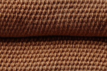  a close up of a brown knitted material with a small amount of light brown yarn on the top of the material and a small amount of light brown yarn on the bottom of the material.