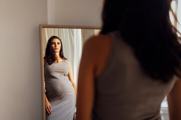 Close up of female portrait of beautiful pregnant in grey dress touching her belly.