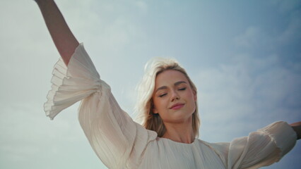 Romantic girl enjoy wind standing sunlight close up. Woman raising hands to sky.