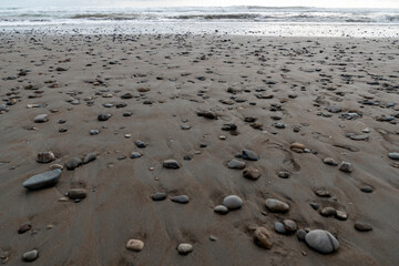 Beach with stones pebbles in dark sand Dominical Costa Rica
