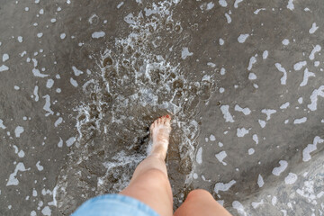 Women feet splashing and walking on the beach with red nail polish 