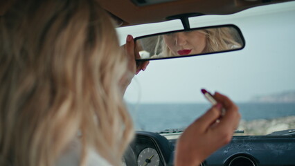 Woman looking makeup car mirror enjoying reflection sensual red lips close up. 