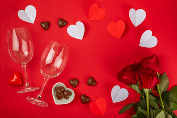 Valentine's Day concept. Valentine's Day background. Gifts, candles, confetti, envelope - postcard, candy, glasses, wine and a bouquet of roses on a red background. Flatley.Valentine's day celebration