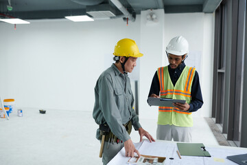 Construction worker talking to builder about details of blueprint