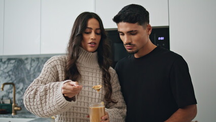 Happy couple cooking together at home. Focused woman holding peanut butter