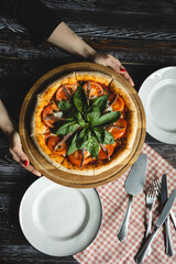 Appetizing pizza with tomatoes, anchovies and basil on a wooden background. Fluffy pizza with crispy sides.
