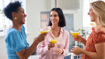 Three Mature Female Friends At Home Having Fun Mixing And Drinking Cocktails Together