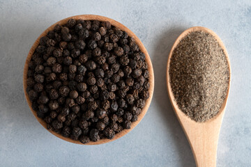 Ground black pepper with grains of black pepper on bright background 
