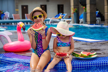 Children eat watermelon near the pool. Selective focus.