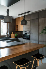 cuisine aménagée moderne composée de bois naturel et béton avec des éclairage suspendu de type...