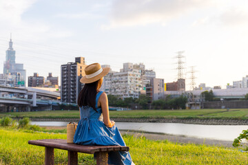 Woman sit beside the river park in Taipei city in the evening