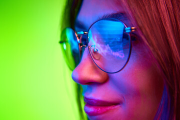 Focused developer, woman wears glasses working on computer looking at programming code which reflecting in glasses. Concept of trading, financial growth, technology, cyber security. Ad
