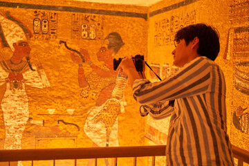 a tourist watching the  sculptural details on the wall of the temple of the Tutankhamun king,...
