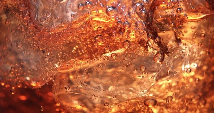 Super slow motion macro of ice cube is falling in campari or aperol spritz cocktail in transparent glass is being mixed by bartender in bar or club.