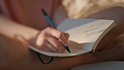 Hands writing personal journal in sunlight closeup. Calm girl rest morning bed