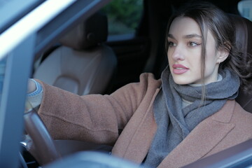 Portrait of a serious young woman driving a car - obrazy, fototapety, plakaty