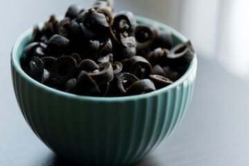 Cut Black Olives in Small Blue Bowl on Table - Savory Mediterranean Delight