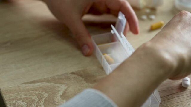 Woman sorting pills in a pill box, close-up