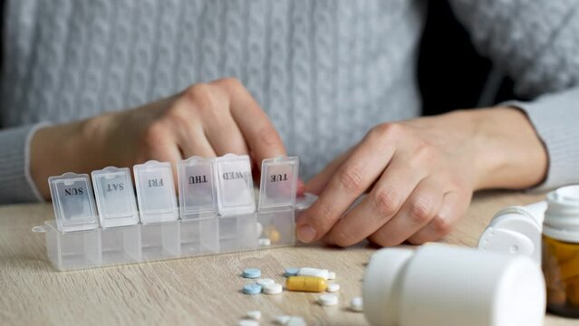 Woman sorting pills in a pill box, close-up