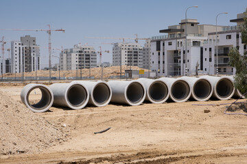 Laying sewer Concrete drainage pipe on construction site between residential areas in Israel. New...
