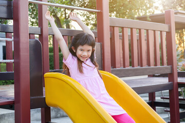 Fototapeta na wymiar Cute asian girl playing on the slide in the playground