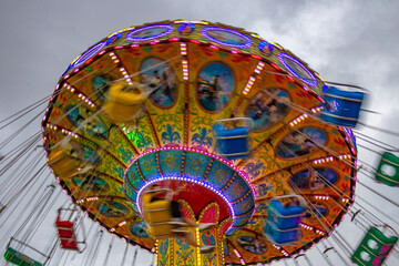 Um brinquedo de rotação em movimento, em um parque de diversões, em um final de tarde nublado.