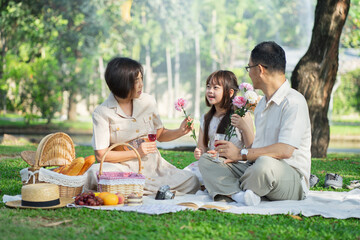 Happy asian family sharing stories during a picnic in the park.