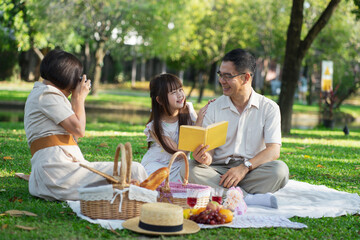 Asian family captures joyful moments during a sunny picnic.