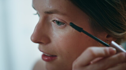 Closeup woman holding mascara brushing eyelashes. Smiling woman admiring visage