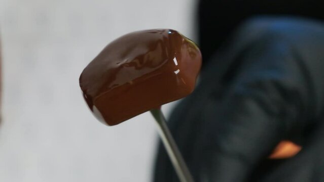 Woman artfully moves stick ensuring homemade culinary creation thoroughly infused with chocolate coating. Woman transforms candy in ,masterpiece