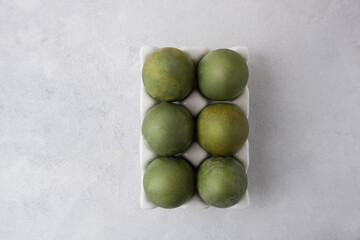 Green eggs in a white tray on a light background. Minimal concept. View from above. Easter eggs. Photo of preparations for Easter.