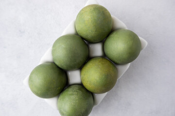 Green eggs in a white tray on a light background. Minimal concept. View from above. Easter eggs. Photo of preparations for Easter.