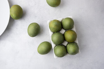 Green eggs in a white tray on a light background. Minimal concept. View from above. Easter eggs. Photo of preparations for Easter.