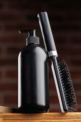Mockup black bottle shampoo for men with comb on dark background brick. Concept spa barbershop cosmetics for man.