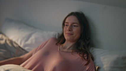 Naklejka premium Closeup girl enjoying morning in bed. Smiling calm female lying soft pillows
