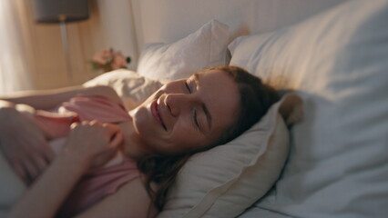 Joyful girl resting bed in morning sunlight closeup. Happy woman waking up early