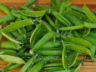 A heap of empty open green pea pods on  wooden background