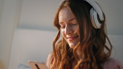 Joyful teenager typing mobile phone in headphones closeup. Carefree girl listen